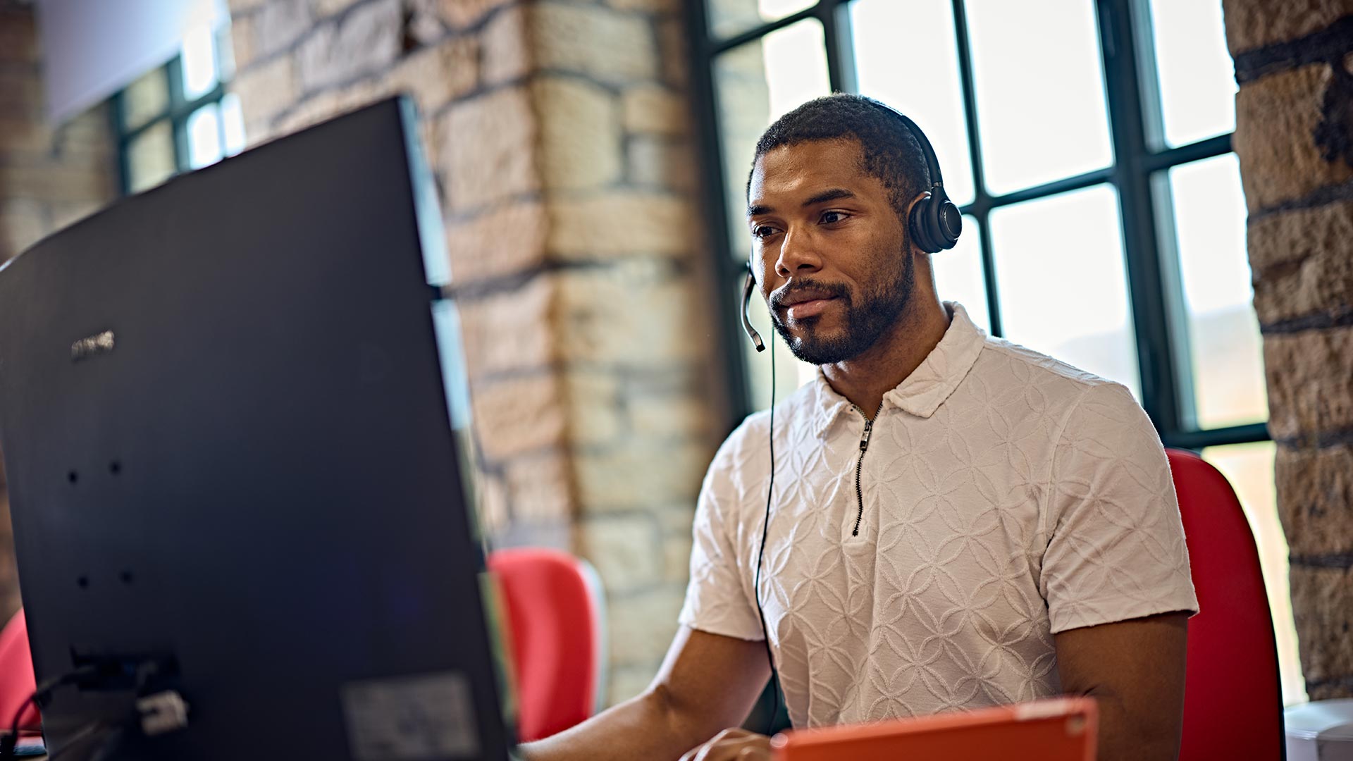 A student wearing a headset, working on a computer.