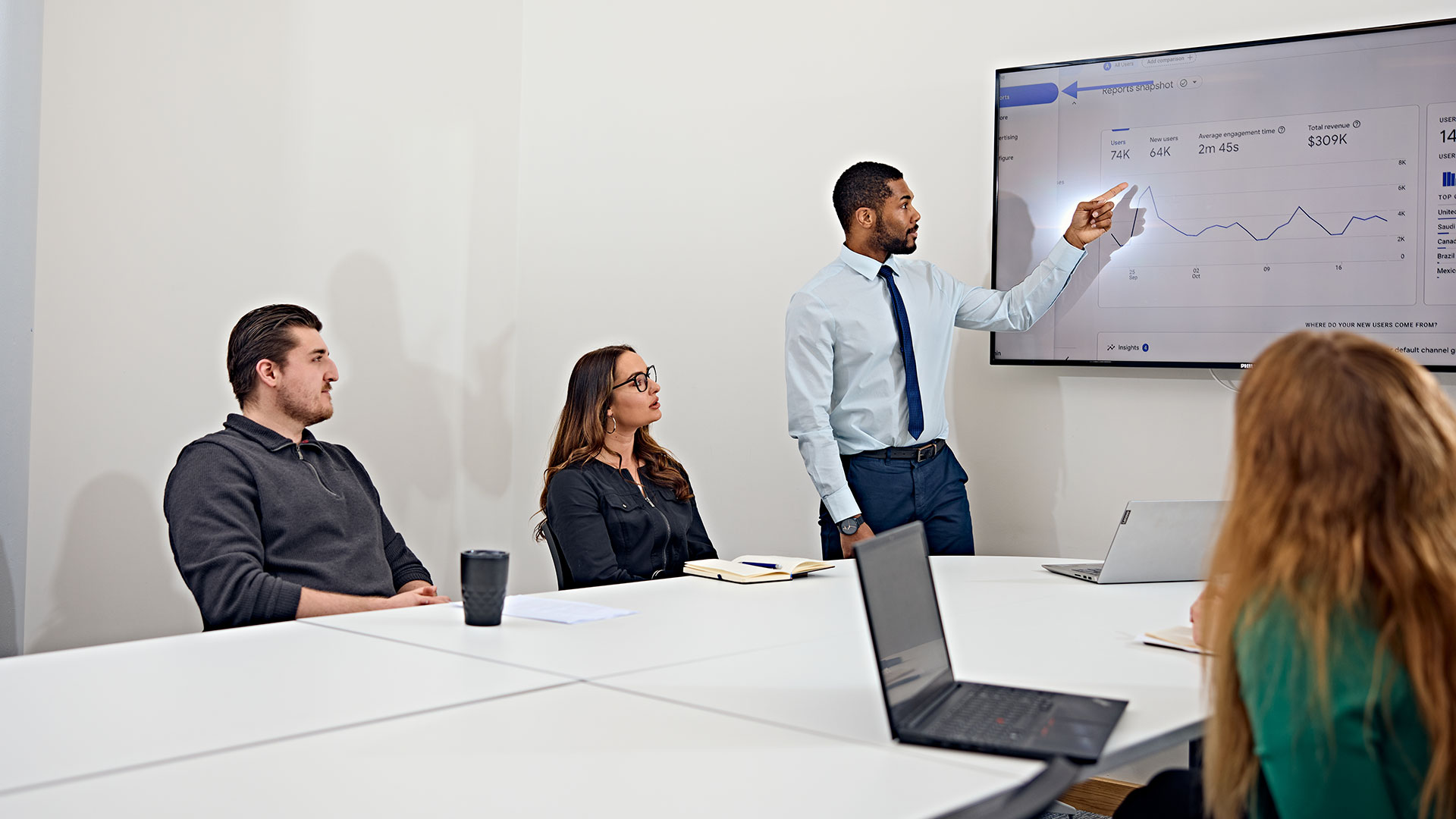 A professional leading an in-person business meeting with three colleagues.