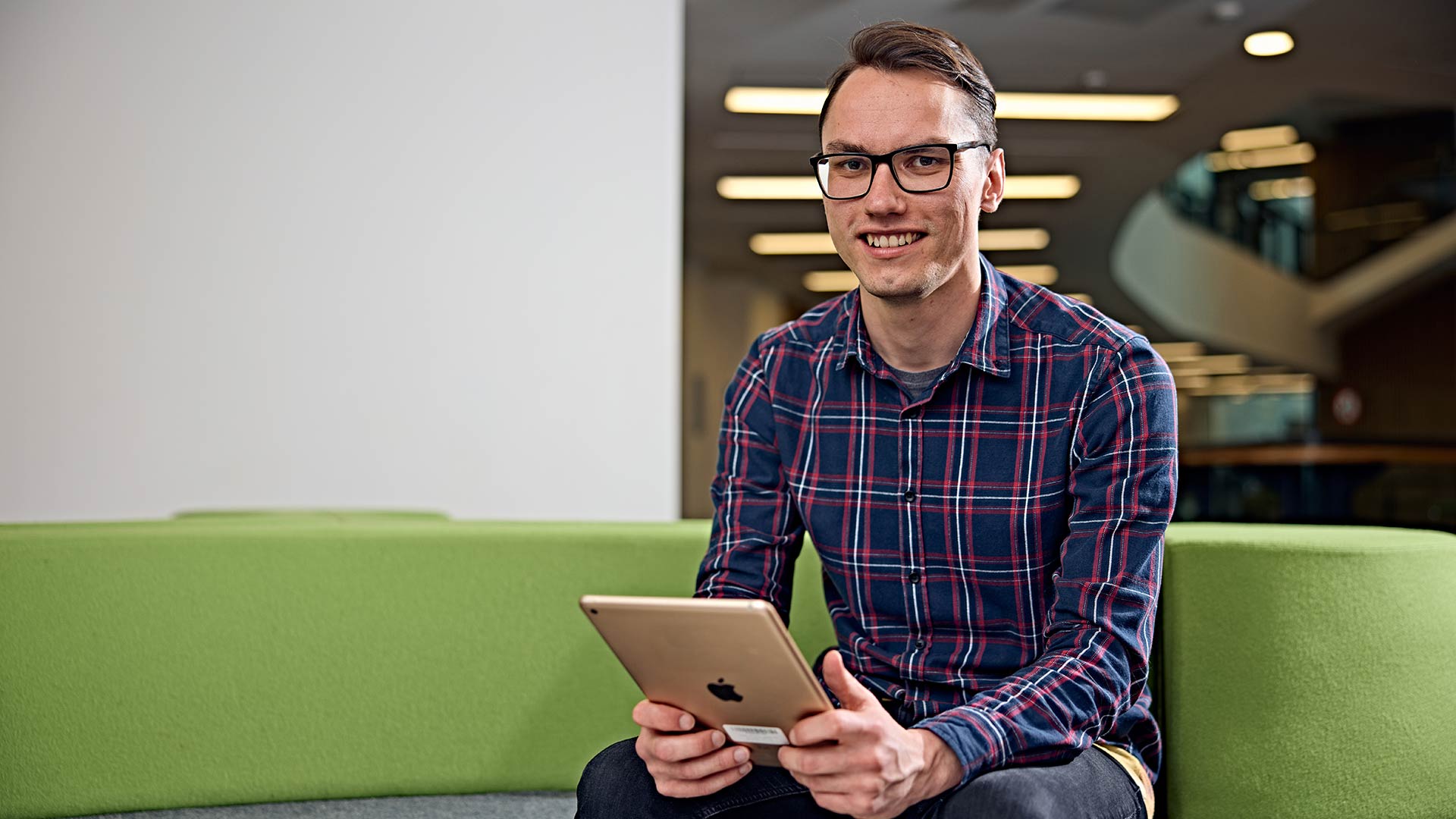 A student sat holding a tablet device.