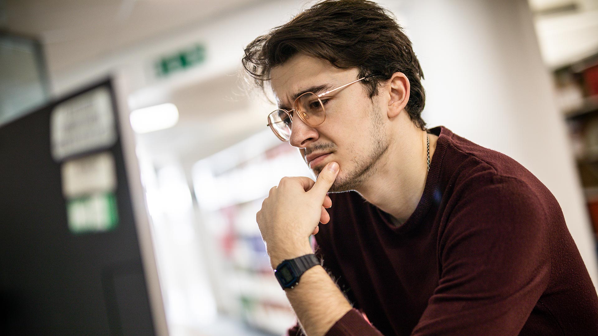 A student looking inquisitively at a computer screen.