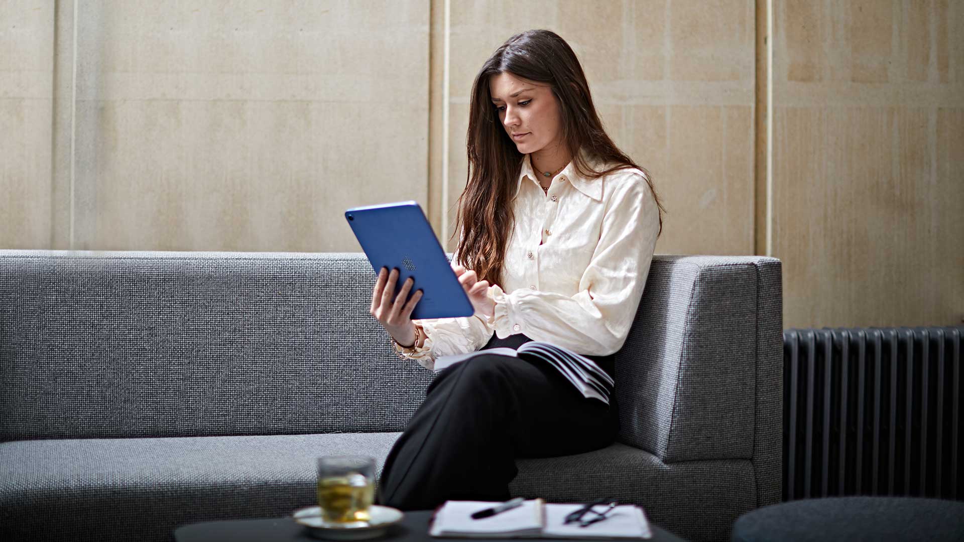 A student in a café, using a tablet device to study.