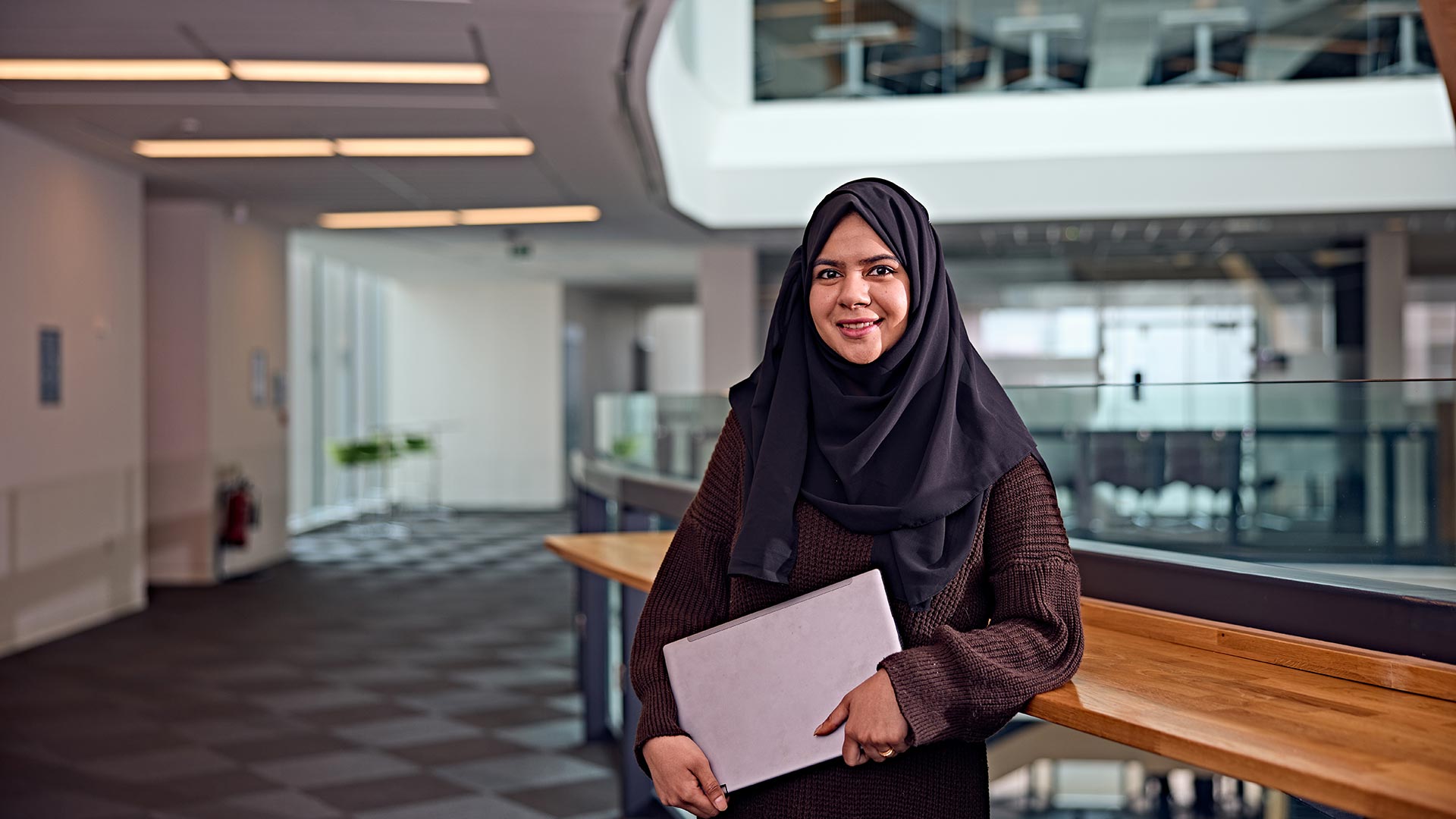 A student stood holding a laptop.