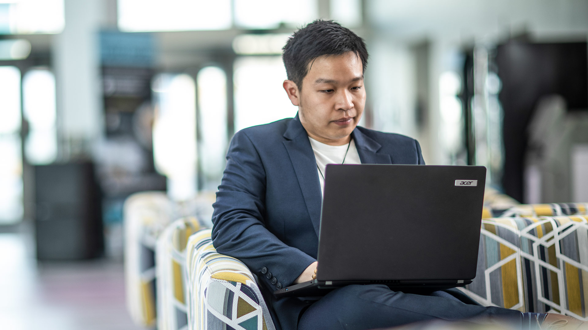 A student sat working on a laptop, placed on their lap.