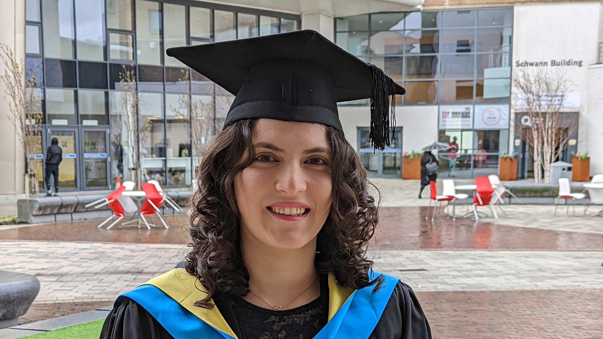 Fuzhan in her graduation gown and hat, holding a certificate.