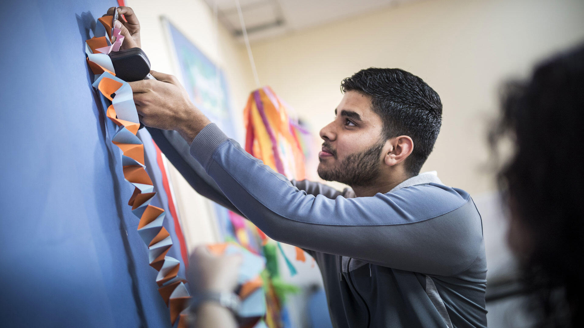 Male student putting up display in Early Years room