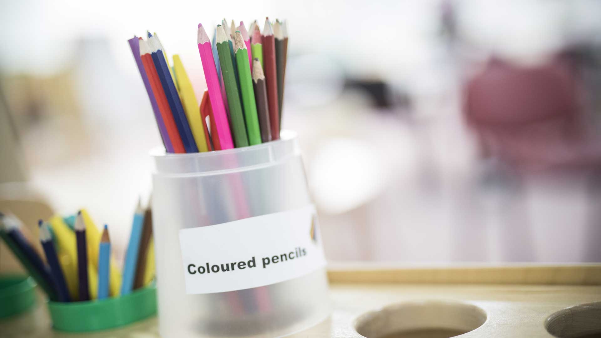 A pot of coloured pencils sat on a desk