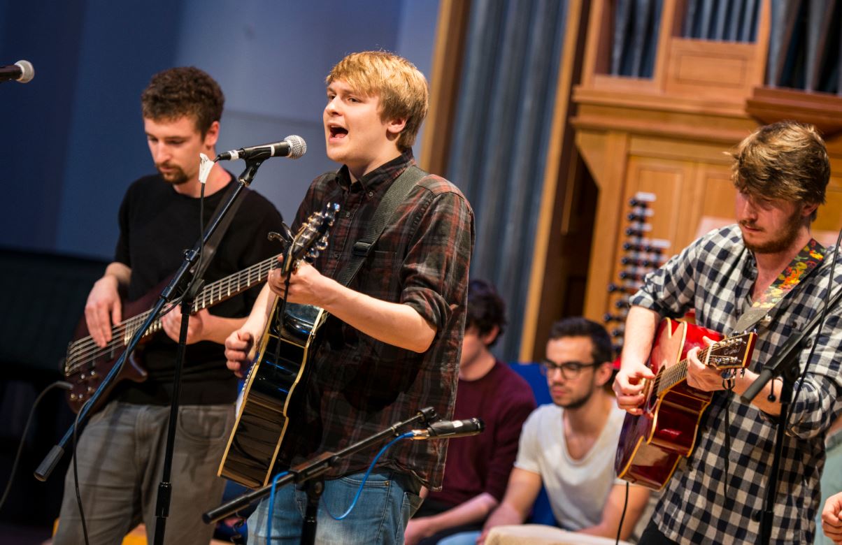 Three students performing with guitars