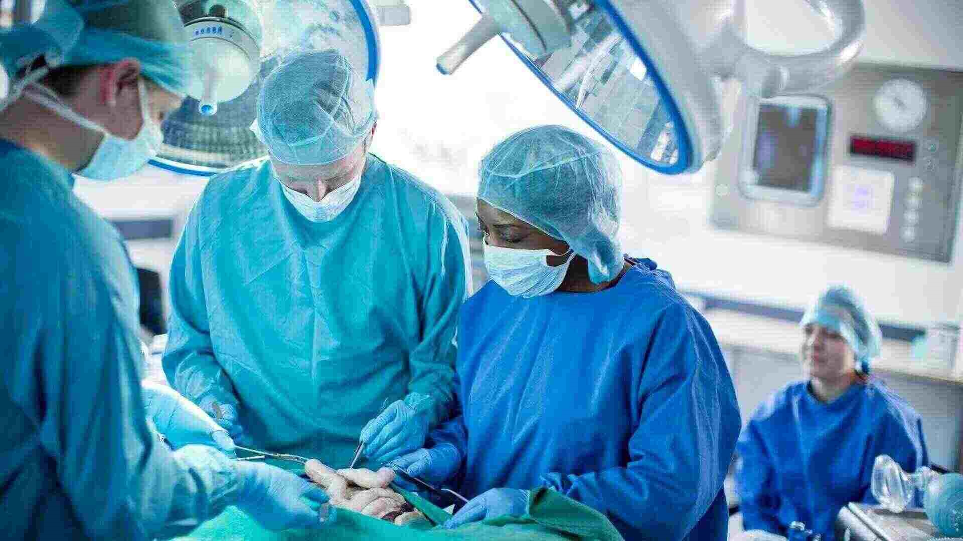 3 students round an operating theatre in the mock ward on campus. They are practising operating techniques and instruments. 