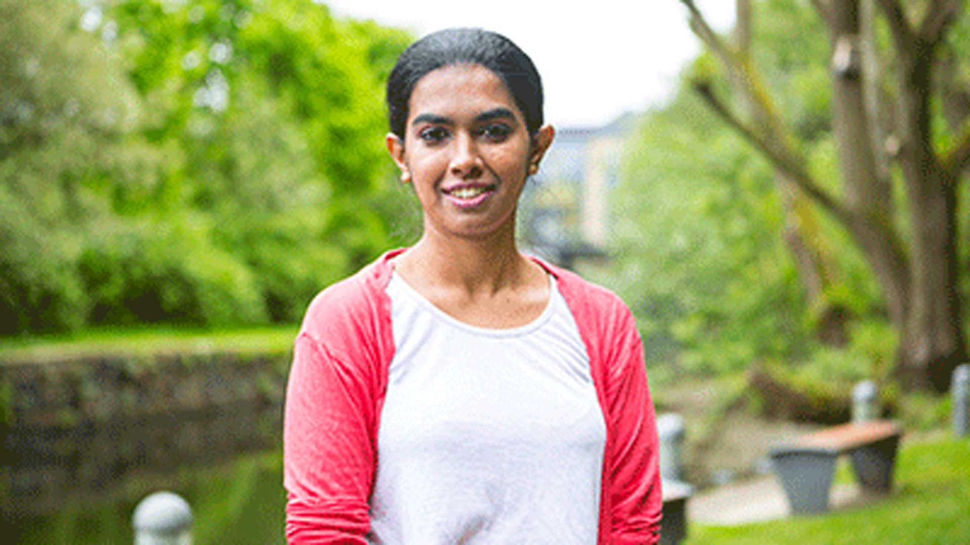 A Sri Lankan student stood outside with trees and greenery behind them.