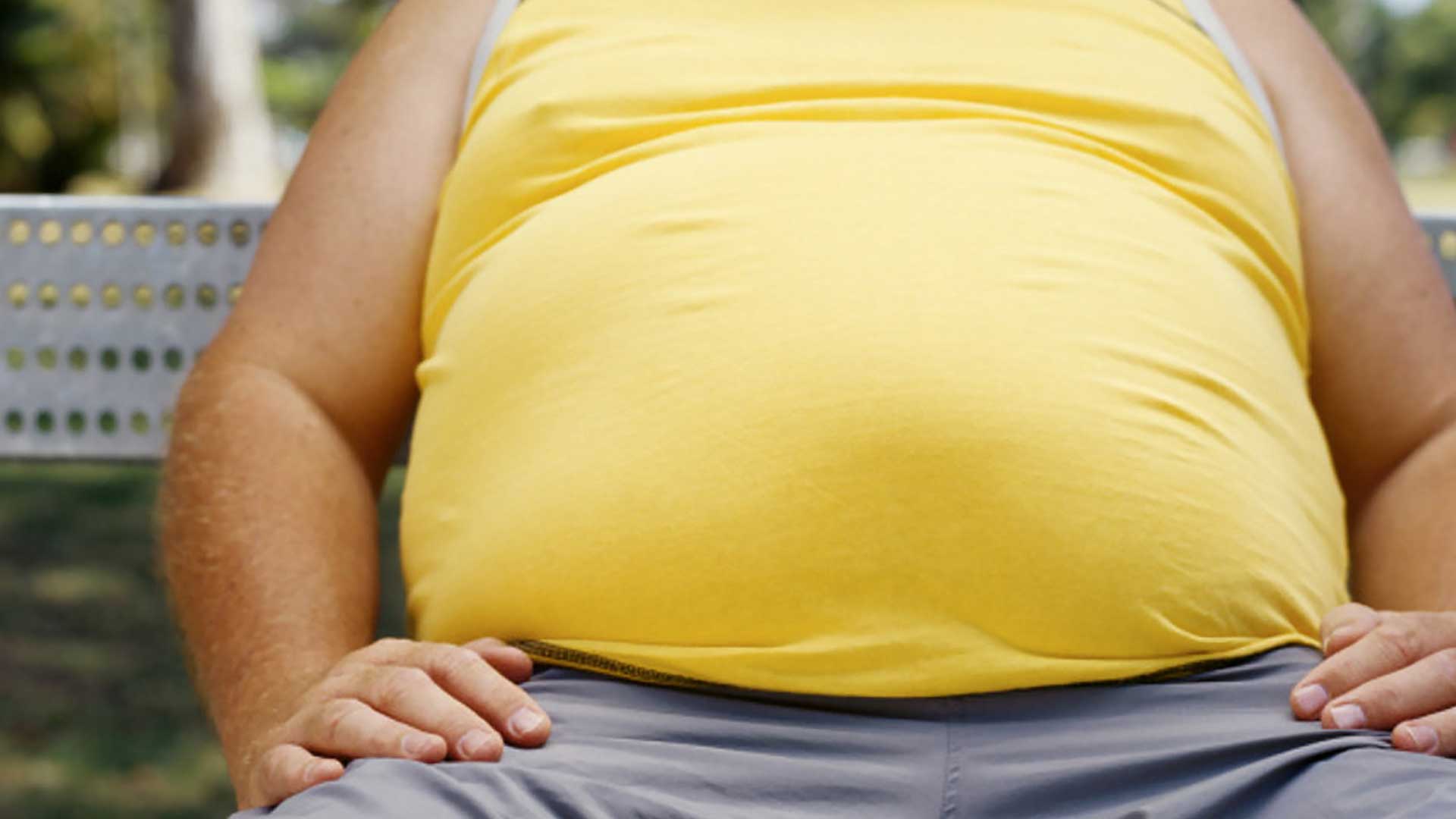 obese man in yellow vest sitting on a bench