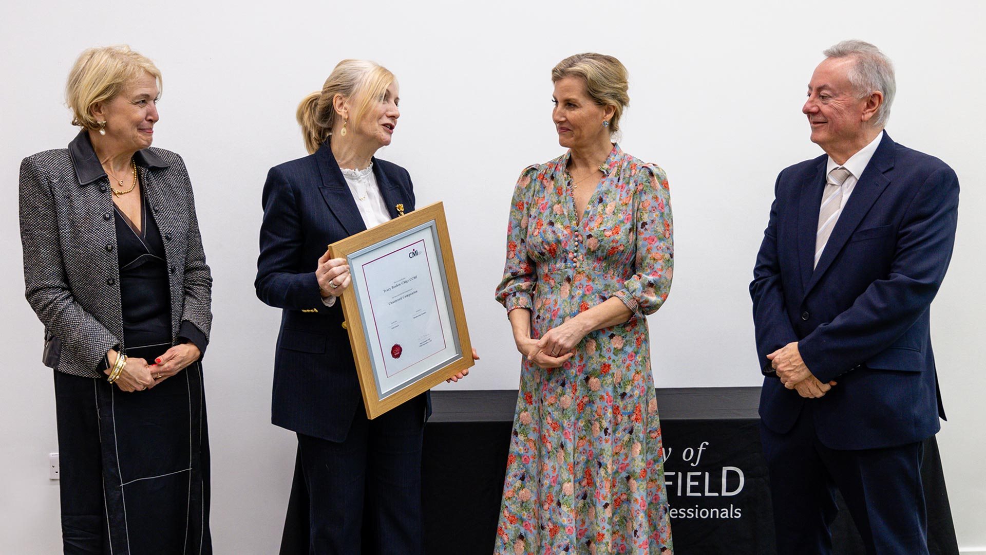 Four people with one being presented with a certificate