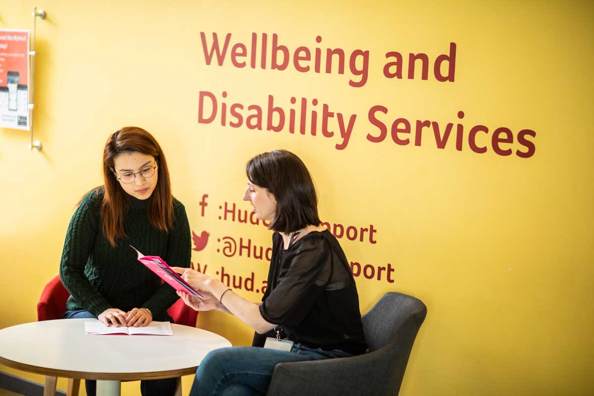 two people talking under a sign for wellbeing and disability