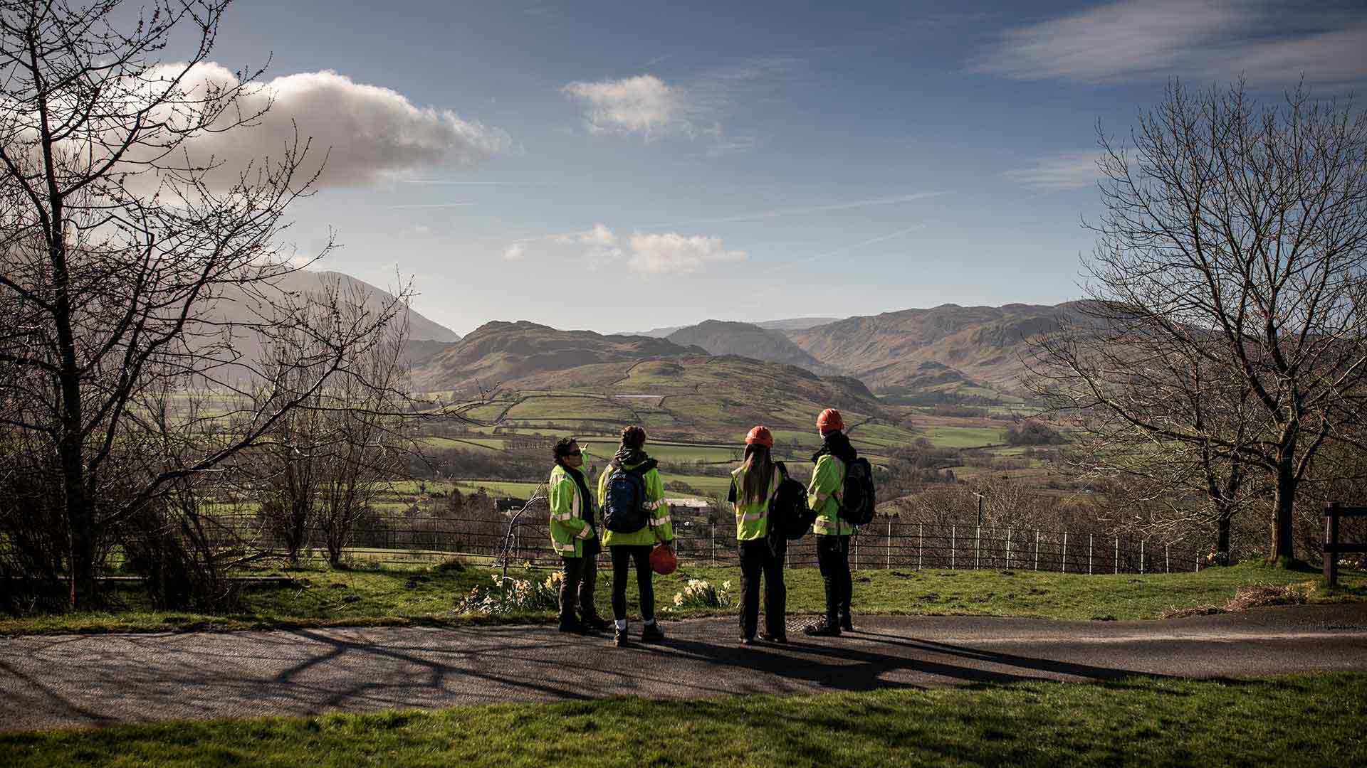 4 students stand looking over a Yorkshire hillside during a geography field trip