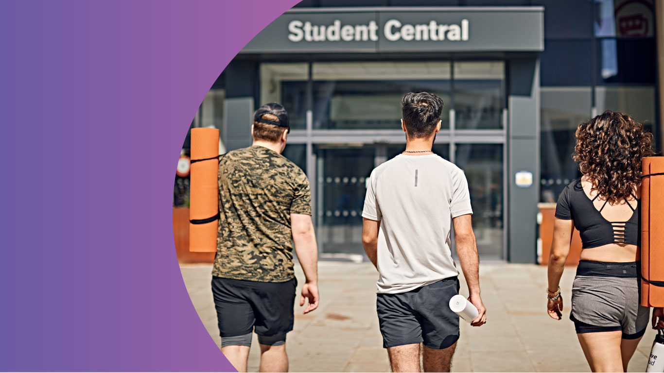 Three students in front of Student Central in gym clothing