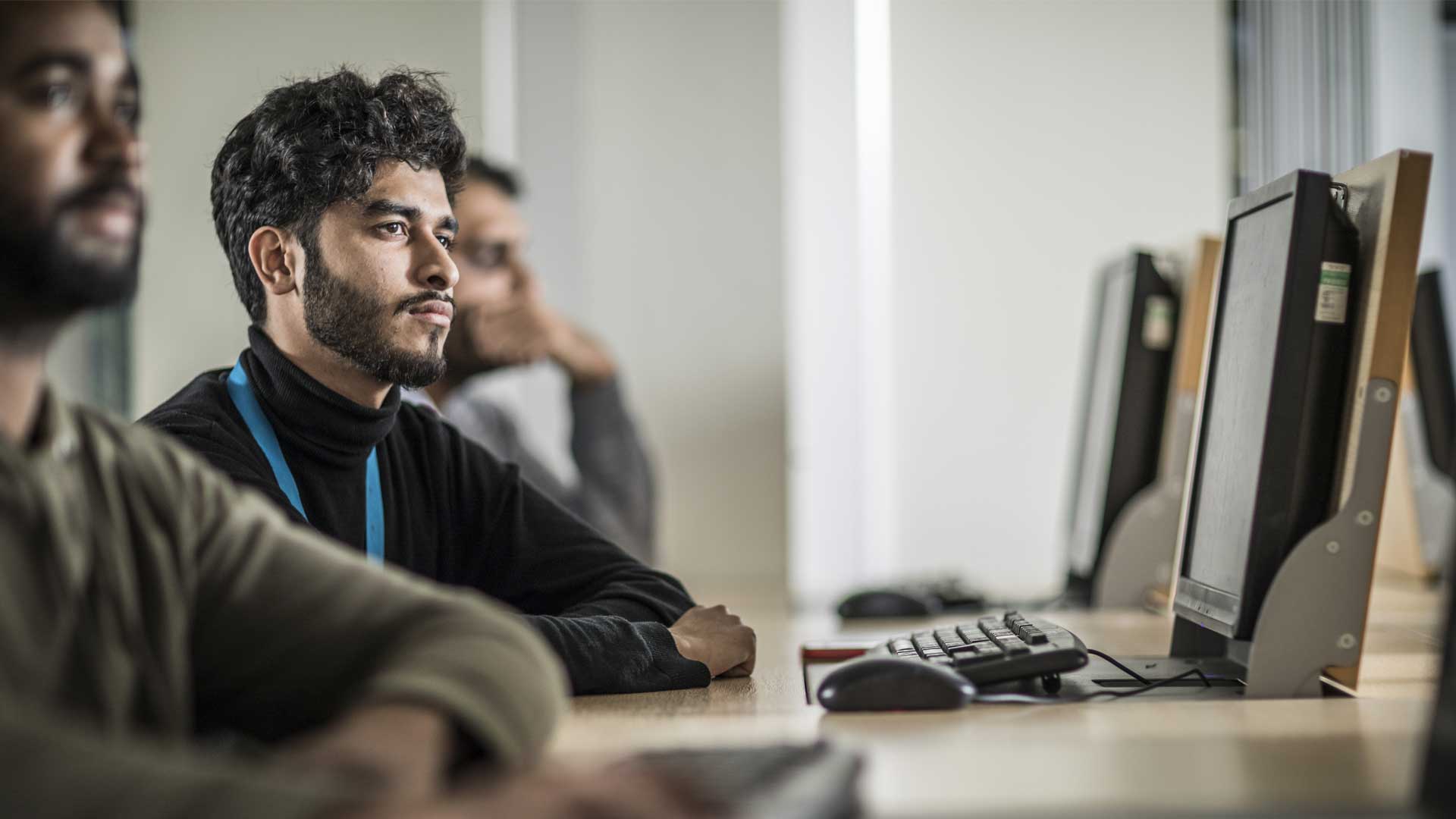 A student stares into the distance while a PC sits in front of him.